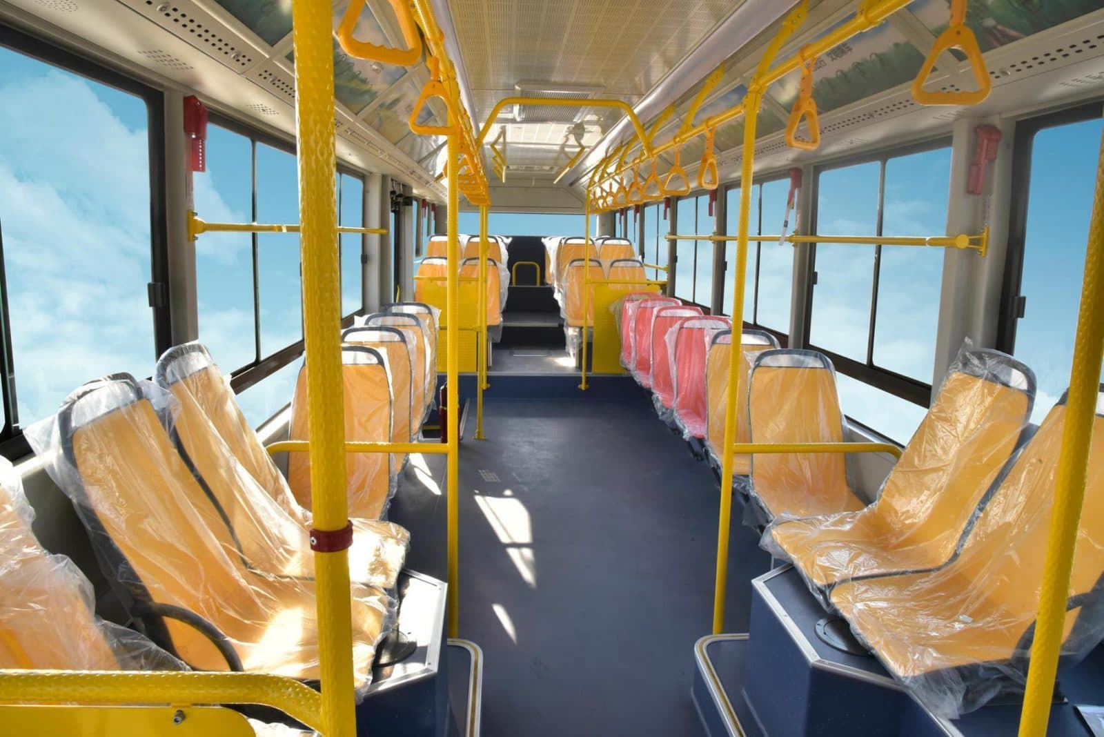 Interior of the Skyworth NJL6126EV looking down the saloon, with yellow grab rails and stanchions.